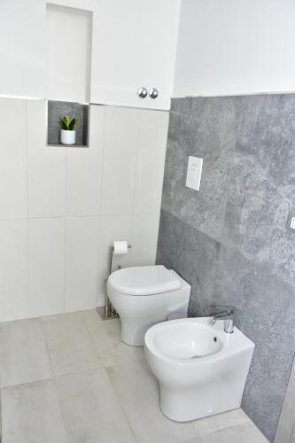 a white bathroom with a toilet and a sink at Yllen Rooms in Avola