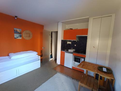 une chambre avec un lit et une cuisine aux murs orange dans l'établissement Studio pour 2 pers à Montgenèvre - Proximité pistes et commerces - Parking inclus - Petit Budget - FR-1-445-154, à Montgenèvre
