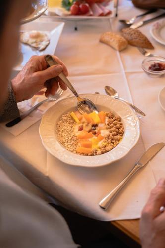 a person eating a bowl of food on a table at Pension Lahn in Rablà