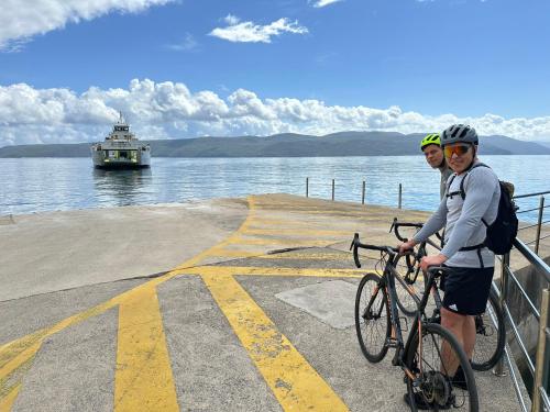 two people on bikes on a pier with a ferry at Luxury Seaview Apartment in Juraši