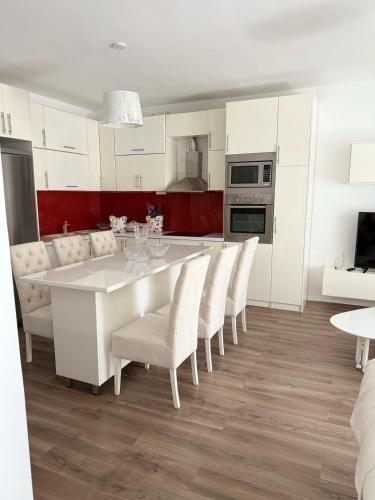 biała kuchnia z białym stołem i krzesłami w obiekcie Join Apartment w Sarandzie