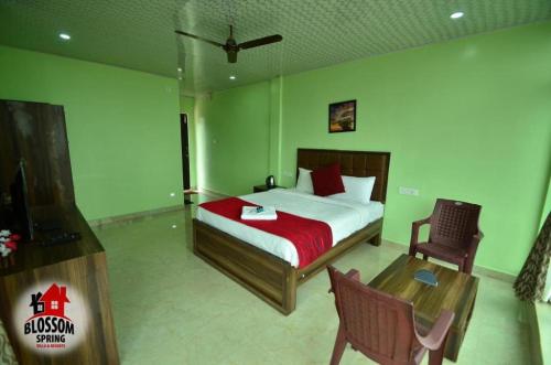 a bedroom with a bed and a table and a chair at Blossom Spring Villa in Ooty
