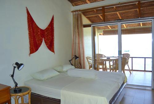 a bedroom with a bed and a balcony with a table at Freddies Santai Sumurtiga in Sabong