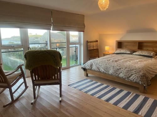 a bedroom with a bed and a chair and windows at Large Stunning Sea View Coastal Townhouse in Killough