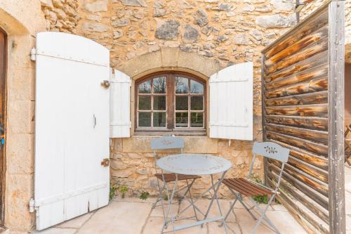 d'une terrasse avec une table et des chaises dans un mur en pierre. dans l'établissement Les Buisses - Petit Gite, à Simiane-la-Rotonde