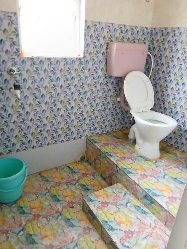 a bathroom with a toilet and a colorful floor at ABDB Homestay in Guwahati