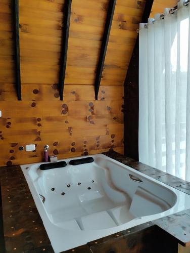 a large white bath tub in a room with wooden walls at Rancho dos lagos in Campo Alegre