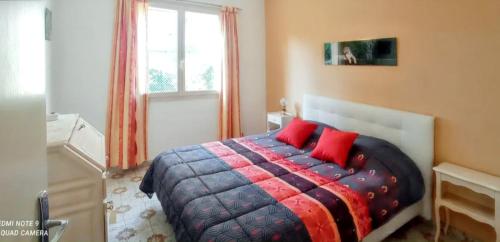 a bedroom with a bed with red pillows and a window at Maison accueillante à Saint-Laurent-du-Var avec jardin in Saint-Laurent-du-Var