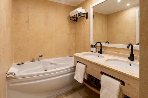 a bathroom with a tub and a sink and a mirror at PONTIANA Thalasso Hotel in Oropesa del Mar