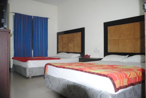 two beds in a hotel room with blue curtains at Hotel Sea Alif in Cox's Bazar