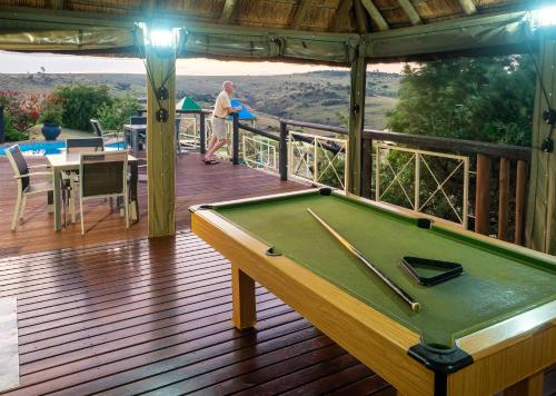 a man standing on a deck with a pool table at Mount Savannah Lodge by Dream Resorts in Krugersdorp