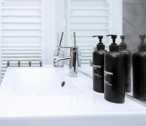 deux bouteilles noires posées sur un lavabo de salle de bain dans l'établissement Lovely apartment-near Orly-free private parking, à Athis-Mons