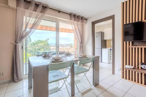 une salle à manger avec une table et des chaises et une grande fenêtre dans l'établissement Short Time Suites Fréjus 