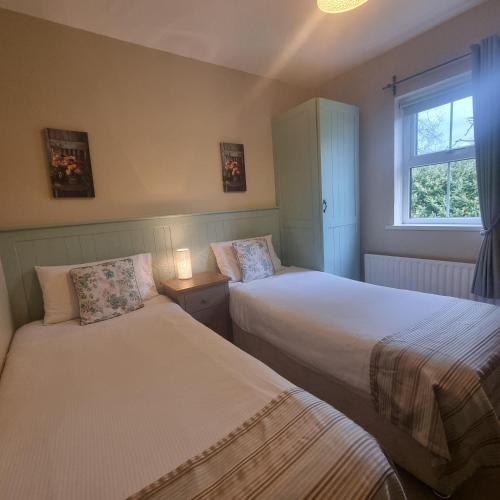 a bedroom with two beds and a window at McGuire's Red Door Cottages in Drumshanbo