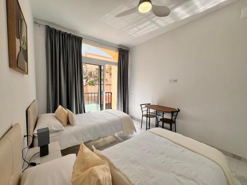 a bedroom with two beds and a table and a window at Casa Fe in Morro del Jable