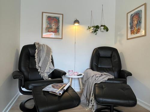 two black chairs and a table in a room at Nærvær i Skagen in Skagen
