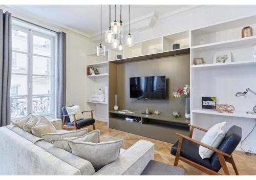 un salon avec un canapé et une télévision dans l'établissement Apartment Le Marais by Studio prestige, à Paris