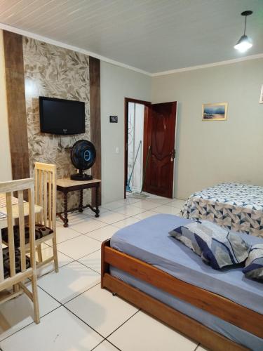 Un dormitorio con una cama y un televisor en una pared. en AH Amabille House, en Serra Negra