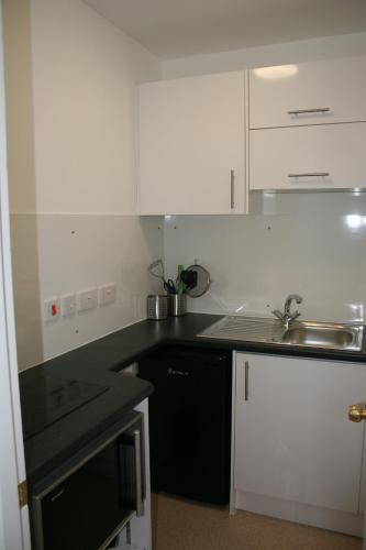 a kitchen with white cabinets and a sink at Byways Serviced Apartments in Salisbury