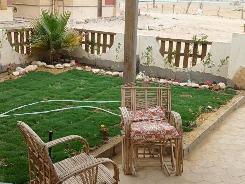 a patio with two chairs and a table and a lawn at Peace and Love Chalet , Laguna view Ras Sedr in Raʼs Matarma