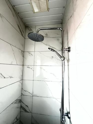 a shower in a bathroom with white marble walls at McGuire's Red Door Cottages in Drumshanbo