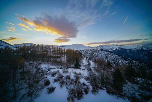 une vue aérienne d'une chaîne de montagnes enneigée avec le coucher du soleil dans l'établissement HSH Huez Sweet Huez, à L'Alpe-d'Huez