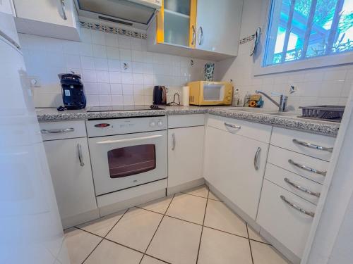 une cuisine avec des armoires blanches et un four à plaques de cuisson dans l'établissement Maison avec jardin et parking, proche des plages, à Fréjus