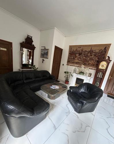 a living room with a black leather couch and chairs at Velez Ház in Budapest