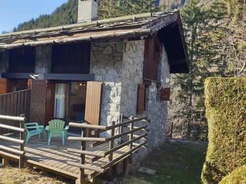 une cabane avec une terrasse en bois et une chaise verte dans l'établissement Petit chalet 4 pers Champagny-en-Vanoise, à Champagny-en-Vanoise