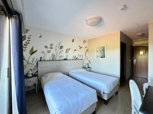 a hotel room with two beds in a room at Hôtel Le Colombier in Moustiers-Sainte-Marie