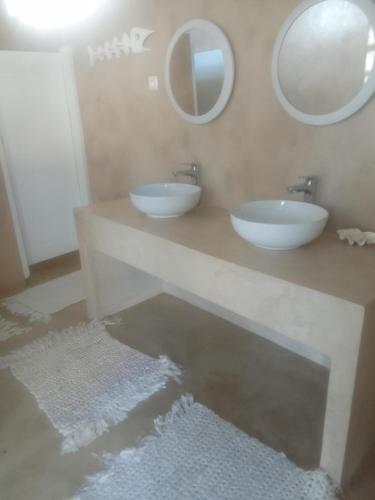 a bathroom with two sinks on a counter with mirrors at Tropicana Guesthouse in Ponta do Ouro