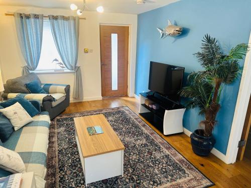a living room with a couch and a tv at Beach Road- short walk to Charlestown, Carlyon Bay & coastal paths- dog friendly in Carlyon Bay