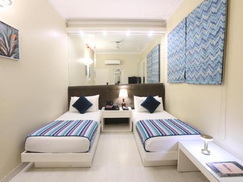 a bedroom with two beds and a desk and a mirror at Hotel Ajanta - Colonial Charm Award Winning Luxury Hotel in the Heart of the City in New Delhi