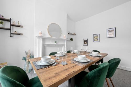 a dining room with a wooden table and green chairs at Cosy 3-Bed House in Blackrod in Blackrod