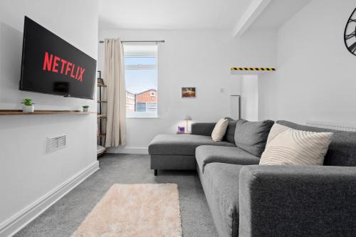 a living room with a gray couch and a tv at Cosy 3-Bed House in Blackrod in Blackrod