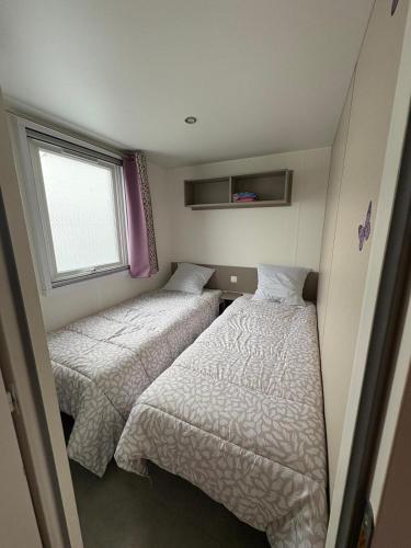 deux lits dans une petite pièce avec une fenêtre dans l'établissement Mobil-home Elite 4-6 pers - Vias Camping La Carabasse, à Vias