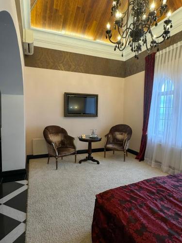 a bedroom with two chairs and a table and a tv at La Gioconda Boutique Hotel in Odesa