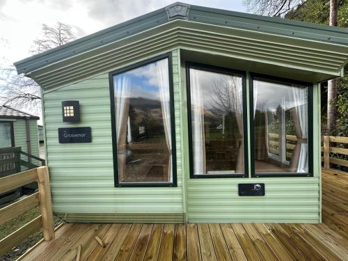 a green tiny house with windows on a deck at The Grosvner 61 in Dunoon