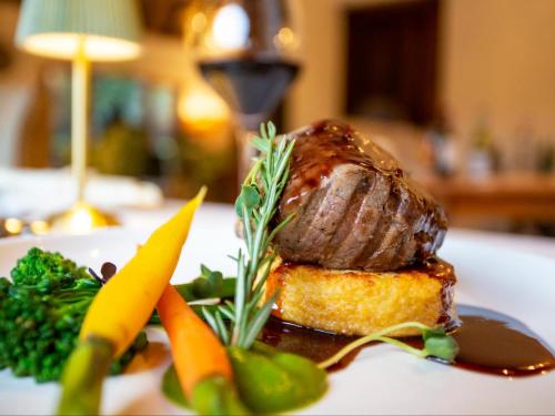 a plate of food with a piece of meat and vegetables at Etnika Manor House in Hoedspruit