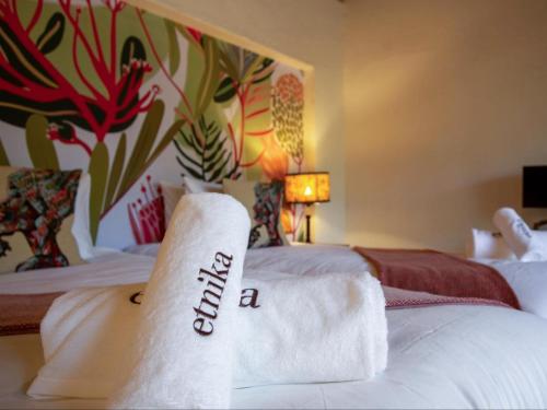 a hotel room with two beds with towels on them at Etnika Manor House in Hoedspruit