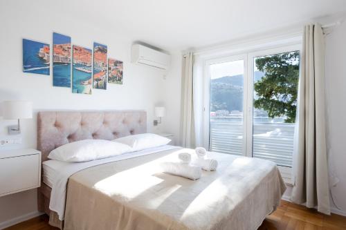 a white bedroom with a bed with towels on it at Orsan Residence Apartment in Dubrovnik