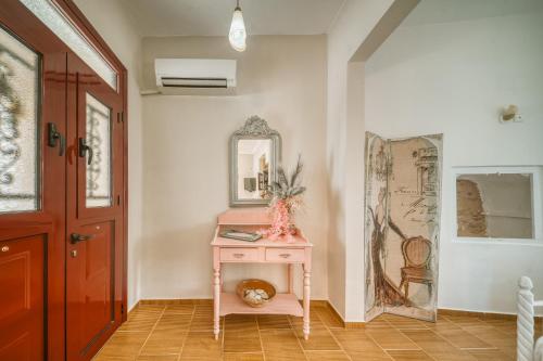 Zimmer mit einem rosa Tisch und einem Spiegel in der Unterkunft Sunflower Kallimasia in Kallimasiá