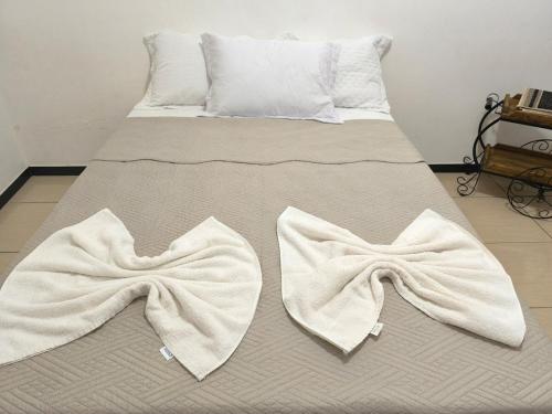 a bed with two white towels on it at Casa Grande com área Gourmet e Garagem in Montes Claros