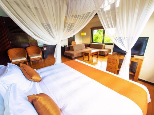 a bedroom with a large bed and a living room at LiVEMAX Amms Canna Resort Villa in Ginoza