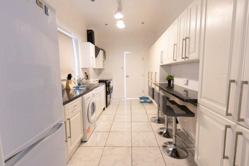 een keuken met witte kasten en een wasmachine en droger bij Luxurious 5 bedrooms apartment and a living room in 7 Sydenham Road, Oxbridge, Stockton, Stockton-on-Tees, TS18 4DG in Stockton-on-Tees