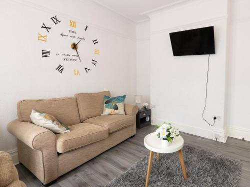 een woonkamer met een bank en een klok aan de muur bij Luxurious 5 bedrooms apartment and a living room in 7 Sydenham Road, Oxbridge, Stockton, Stockton-on-Tees, TS18 4DG in Stockton-on-Tees