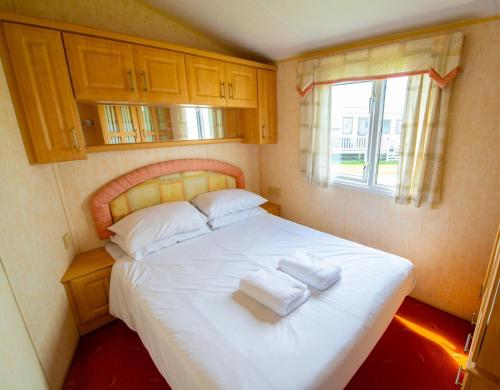 a bedroom with a bed with two towels on it at WW252 Parkdean Camber Sands in Camber