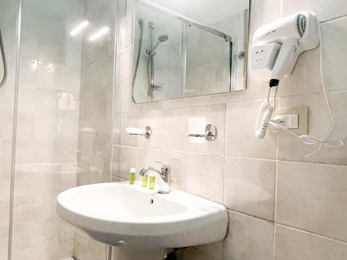 a white bathroom with a sink and a hair dryer at Brain Living Pagani in Pagani