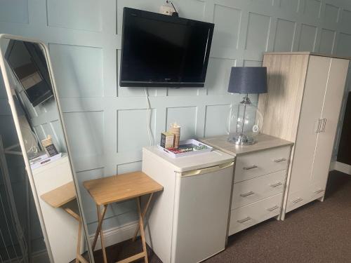 a room with a tv on a wall with a dresser at Crockets Hotel in Newcastle upon Tyne
