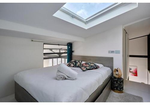 une chambre avec un grand lit avec une lucarne dans l'établissement Duplex Center of Paris by Studio prestige, à Paris